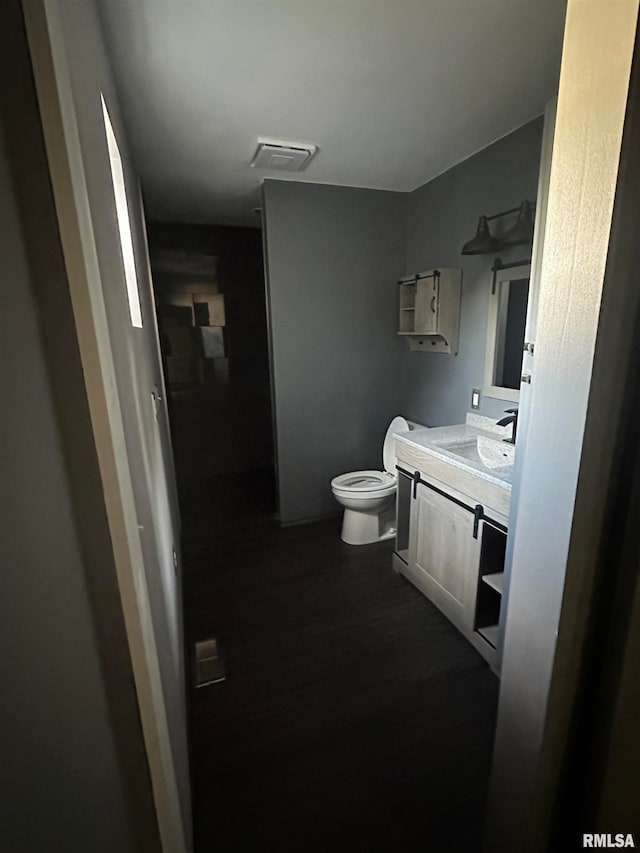 bathroom with hardwood / wood-style floors, vanity, and toilet