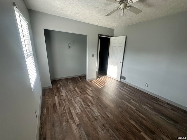 unfurnished bedroom with a textured ceiling, dark wood-type flooring, ceiling fan, and a closet