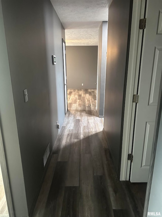 hall featuring a textured ceiling and dark wood-type flooring