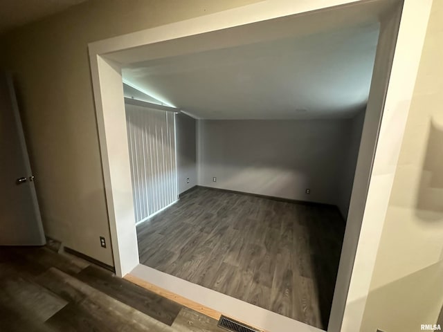 hallway featuring lofted ceiling and dark hardwood / wood-style floors