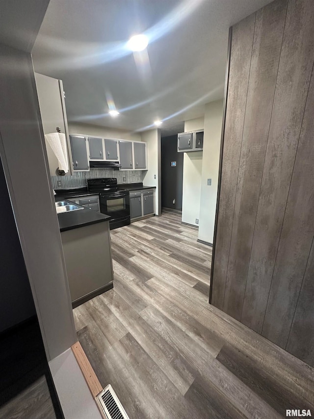 kitchen featuring black electric range oven, sink, tasteful backsplash, gray cabinetry, and light hardwood / wood-style flooring