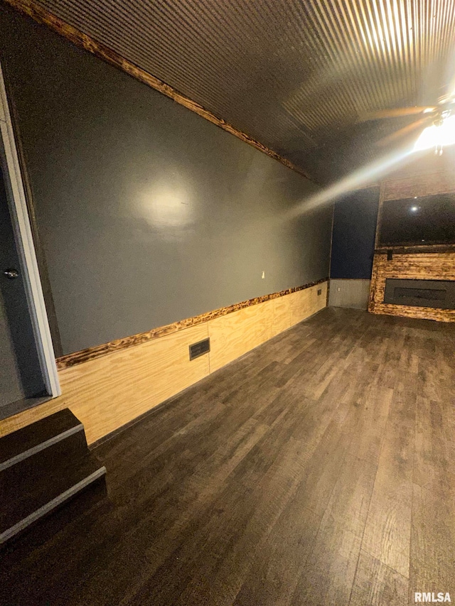 interior space with vaulted ceiling, ceiling fan, a fireplace, and dark wood-type flooring