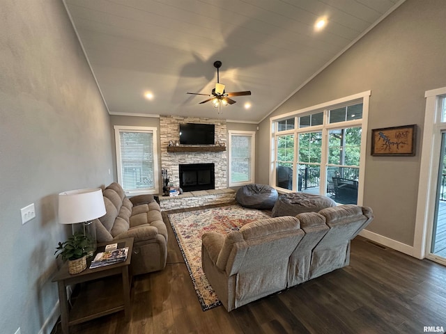 living room featuring ceiling fan, lofted ceiling, ornamental molding, a stone fireplace, and dark hardwood / wood-style flooring