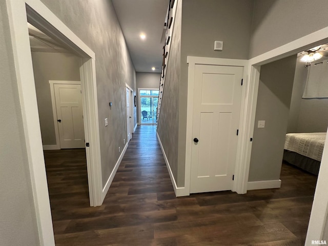 hall with a high ceiling and dark hardwood / wood-style flooring