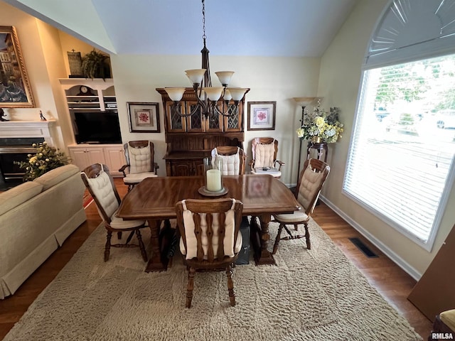 dining space with wood-type flooring, lofted ceiling, and a chandelier