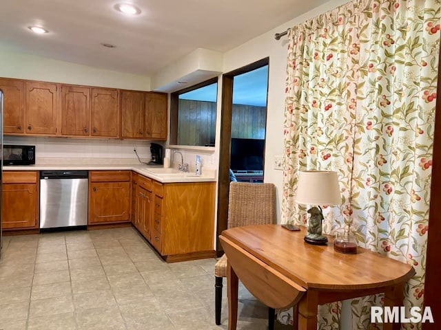 kitchen with brown cabinets, light countertops, a sink, black microwave, and dishwasher