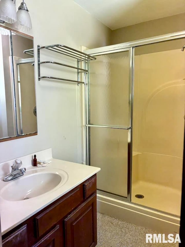 bathroom with a shower with shower door and vanity