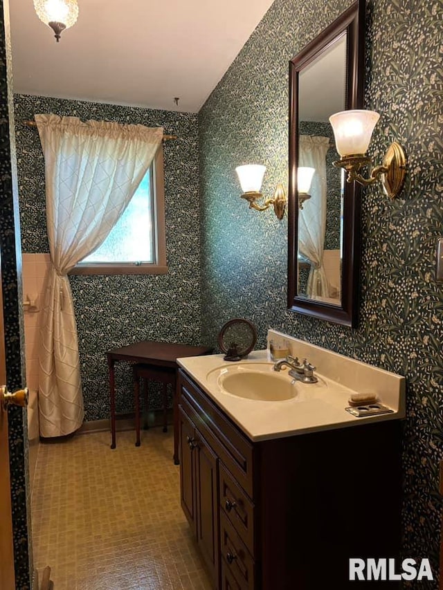 bathroom featuring vanity and wallpapered walls