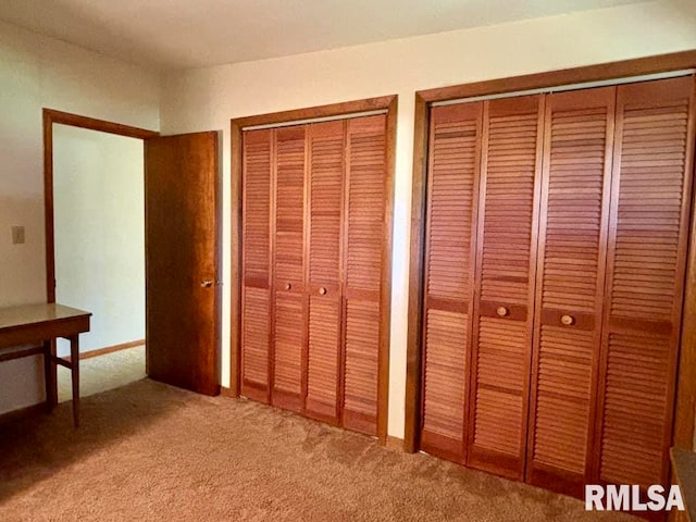 unfurnished bedroom featuring carpet flooring and multiple closets