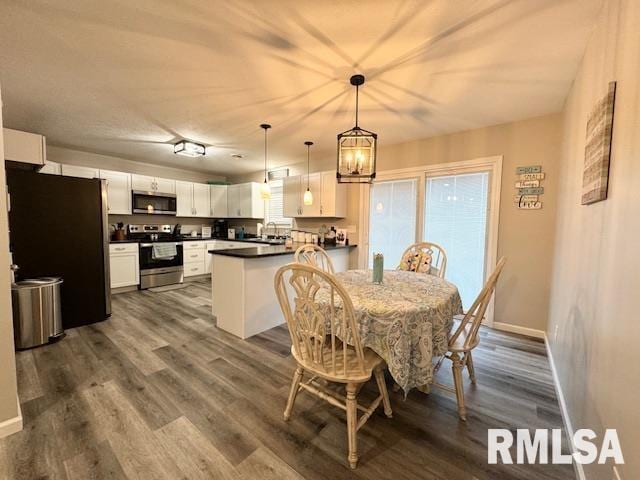 dining area with dark wood-type flooring, an inviting chandelier, and sink