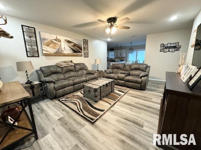 living room with ceiling fan and light hardwood / wood-style flooring