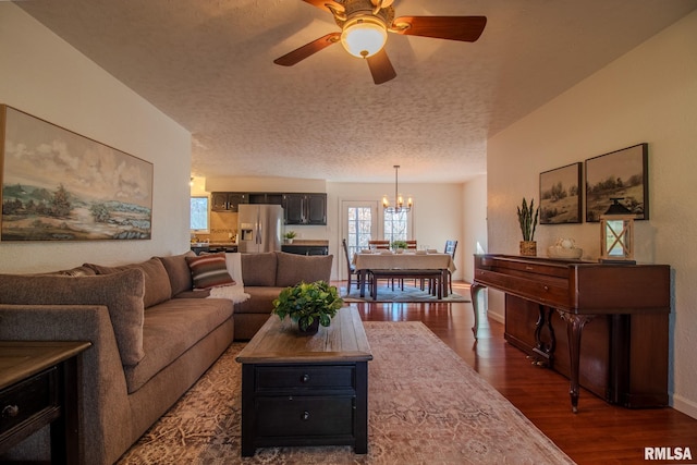 living room with a textured ceiling, ceiling fan with notable chandelier, and dark wood-type flooring