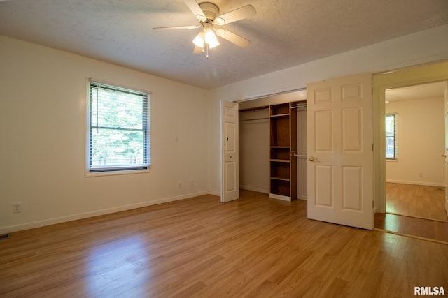 unfurnished bedroom with a textured ceiling, a closet, light hardwood / wood-style floors, and ceiling fan