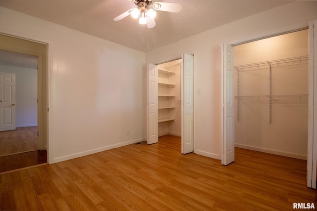 unfurnished bedroom with ceiling fan, a walk in closet, and light wood-type flooring