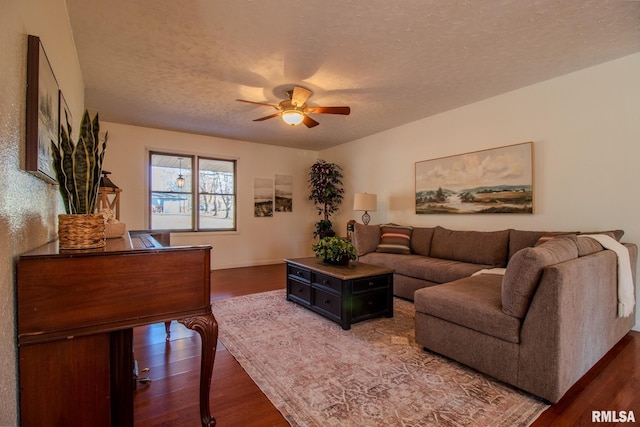 living room with a textured ceiling, dark hardwood / wood-style flooring, and ceiling fan