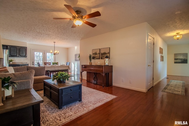 living room featuring ceiling fan with notable chandelier, a textured ceiling, and hardwood / wood-style flooring