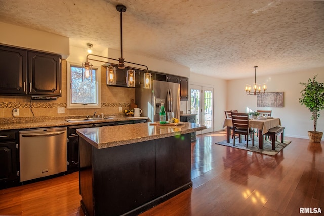 kitchen featuring hardwood / wood-style floors, hanging light fixtures, a notable chandelier, a kitchen island, and stainless steel appliances