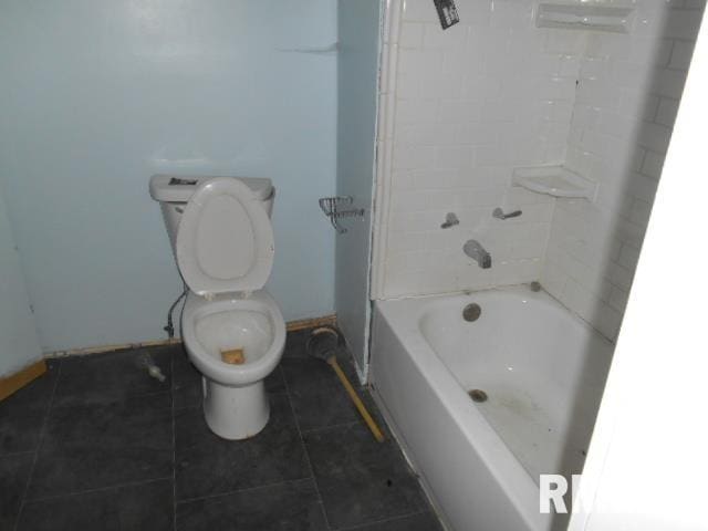 bathroom with tiled shower / bath combo, toilet, and tile patterned floors