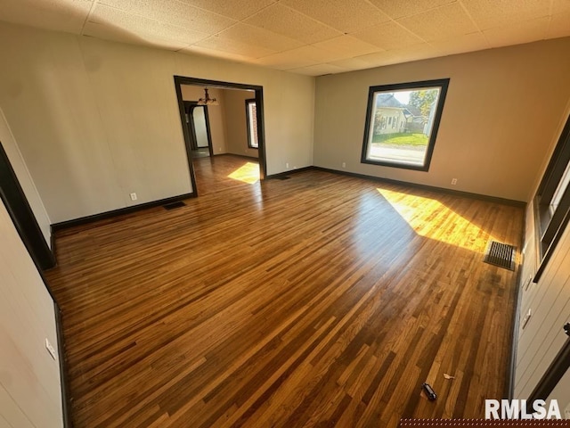 unfurnished room featuring hardwood / wood-style flooring and a drop ceiling