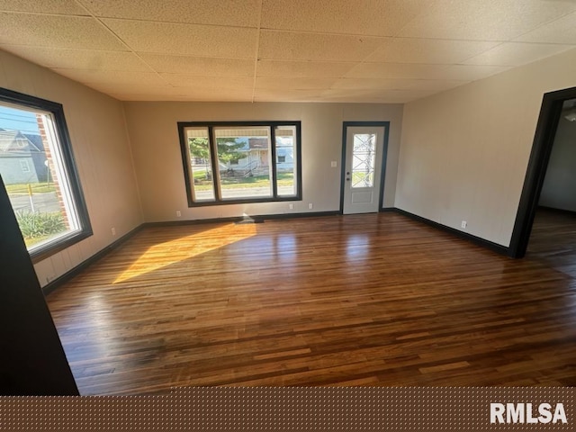 spare room with a paneled ceiling, dark hardwood / wood-style flooring, and a wealth of natural light