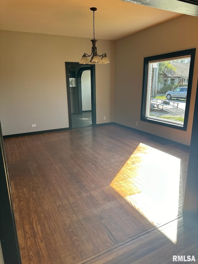 empty room featuring dark hardwood / wood-style floors and a chandelier