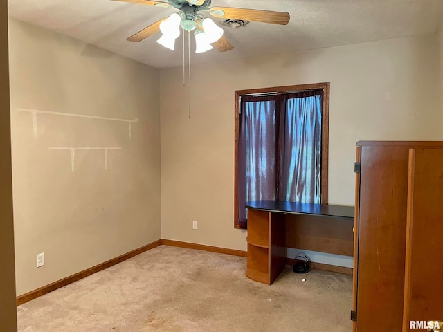 interior space featuring a textured ceiling, ceiling fan, and light colored carpet