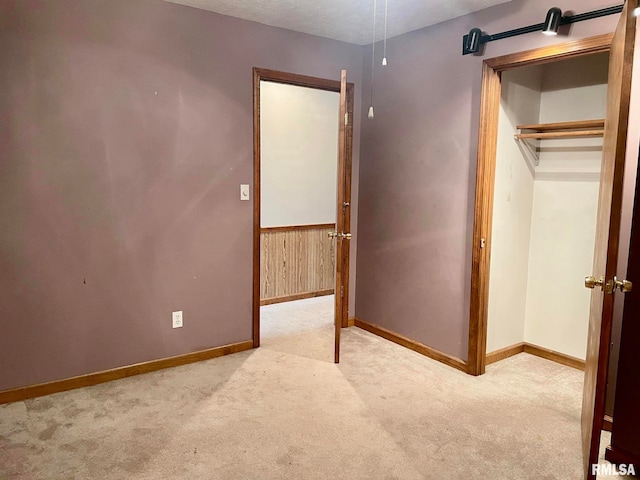 unfurnished bedroom featuring a textured ceiling, light carpet, and a closet