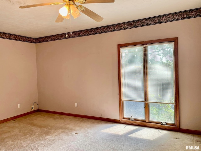 carpeted empty room with ceiling fan and a wealth of natural light