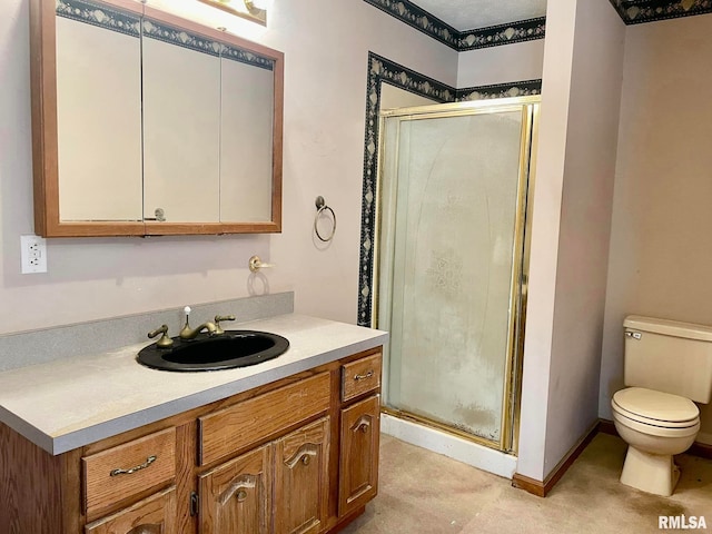 bathroom featuring vanity, a shower with shower door, and toilet