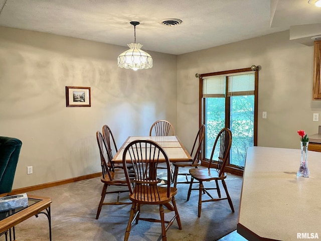 dining area with a textured ceiling, carpet flooring, and an inviting chandelier