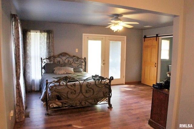 bedroom with a barn door, dark hardwood / wood-style floors, ceiling fan, and french doors