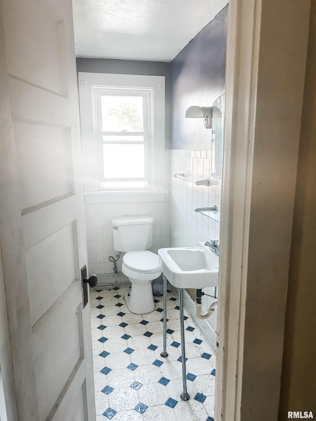 bathroom with tile walls, toilet, and a textured ceiling