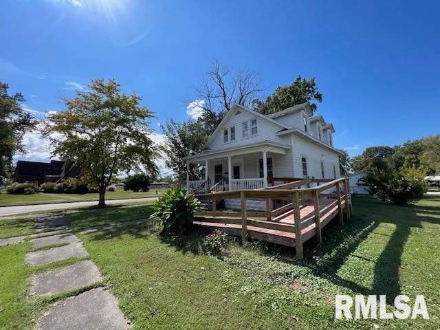 rear view of property featuring a lawn and covered porch