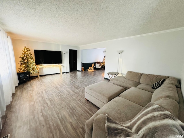 living room featuring wood-type flooring, a textured ceiling, and crown molding