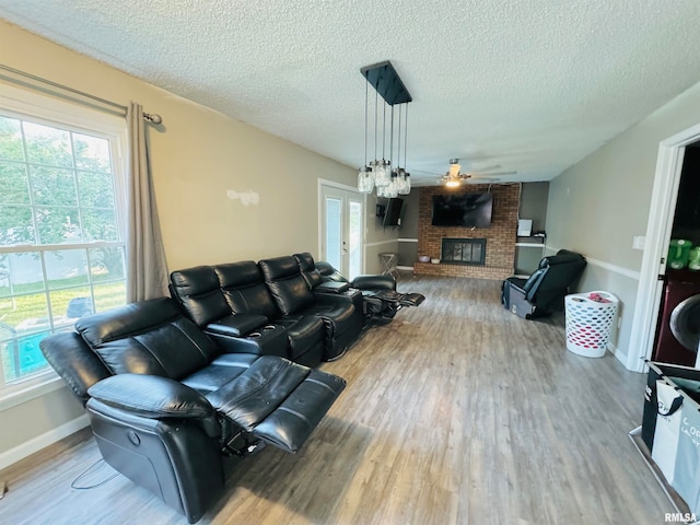 living room featuring a fireplace, hardwood / wood-style flooring, a textured ceiling, and ceiling fan