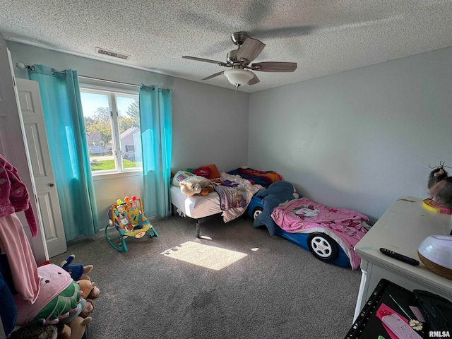 bedroom featuring ceiling fan, carpet floors, and a textured ceiling