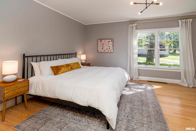 bedroom with crown molding, light hardwood / wood-style flooring, and a chandelier