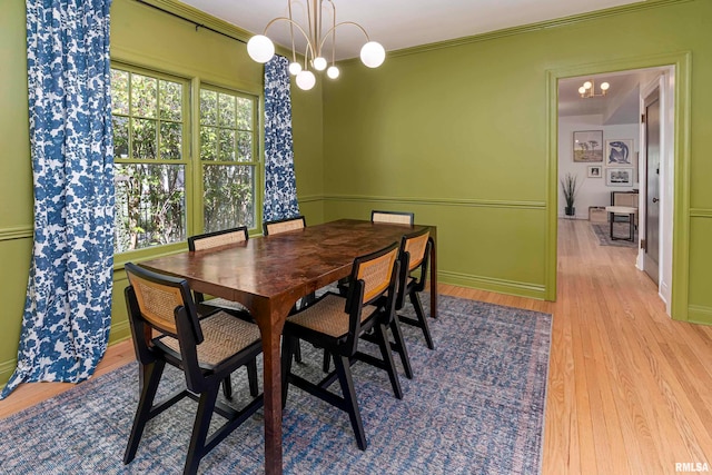 dining area with crown molding, an inviting chandelier, and light hardwood / wood-style floors