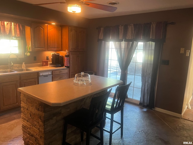 kitchen featuring ceiling fan, a kitchen breakfast bar, sink, and a kitchen island