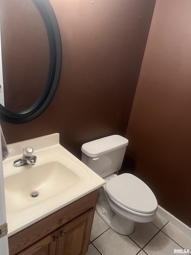 half bath featuring tile patterned floors, vanity, baseboards, and toilet