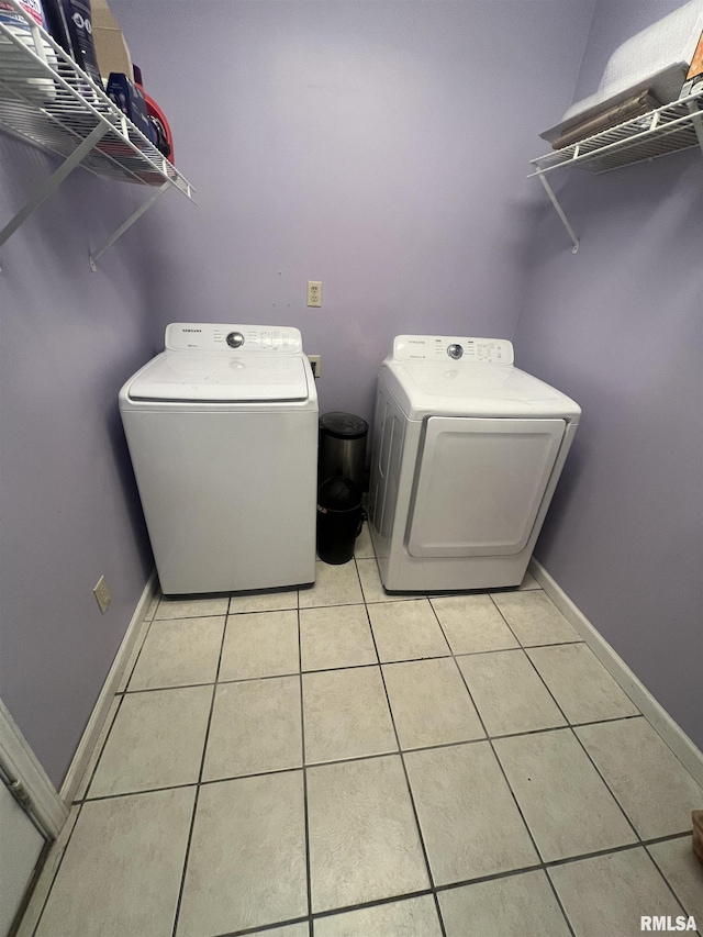 washroom with baseboards, washer and clothes dryer, laundry area, and light tile patterned flooring