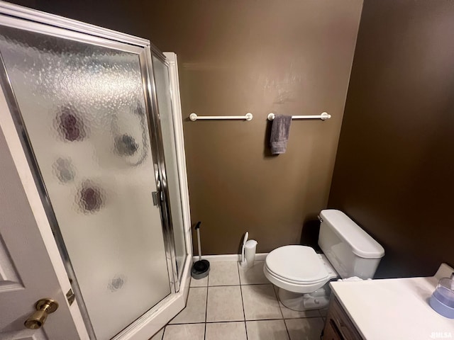 bathroom featuring tile patterned flooring, a shower with door, vanity, and toilet