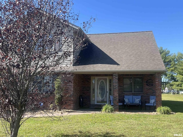 view of front of property with roof with shingles, a front yard, and brick siding