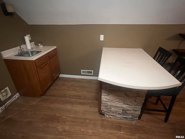 interior space featuring vaulted ceiling, a kitchen bar, dark hardwood / wood-style floors, and sink