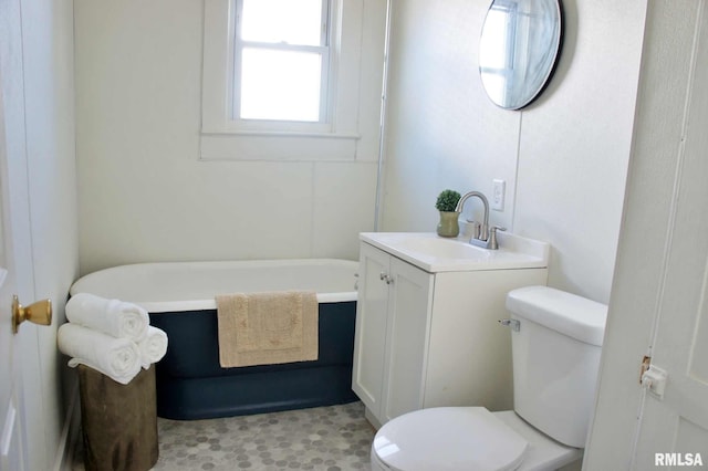 bathroom with a tub to relax in, vanity, and toilet