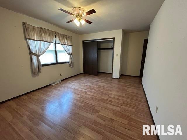 unfurnished bedroom with ceiling fan, a closet, and hardwood / wood-style floors