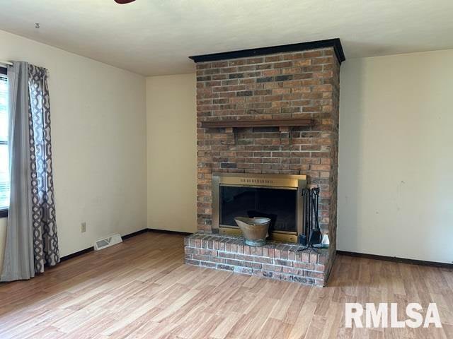 unfurnished living room with a brick fireplace and light hardwood / wood-style floors