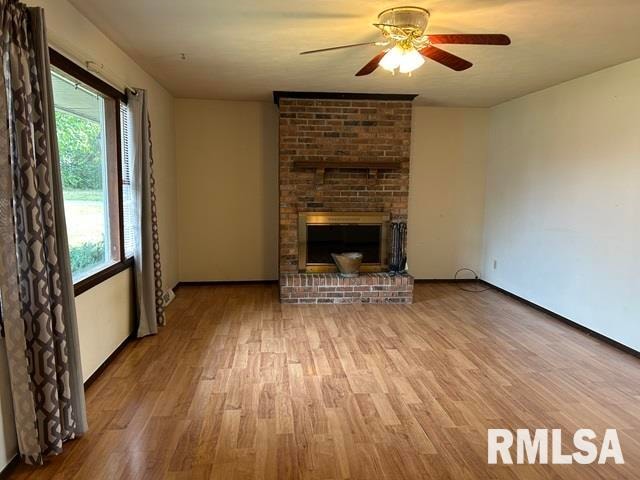 unfurnished living room featuring a fireplace, light hardwood / wood-style floors, and ceiling fan