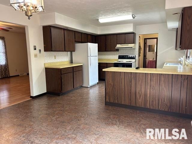 kitchen featuring dark brown cabinetry, kitchen peninsula, white appliances, tasteful backsplash, and dark wood-type flooring