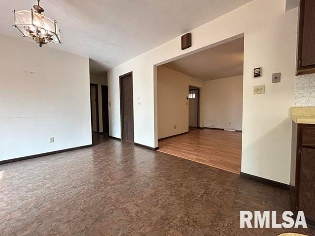 unfurnished room featuring an inviting chandelier and dark hardwood / wood-style floors